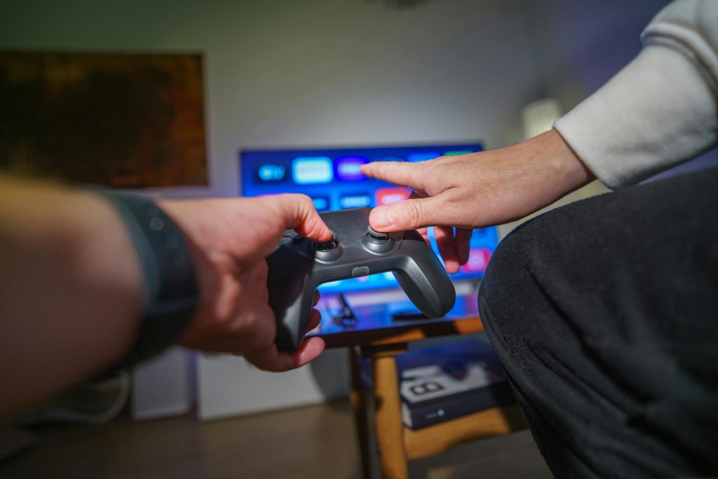 Close-up of hands using a game controller in a cozy living room setting.